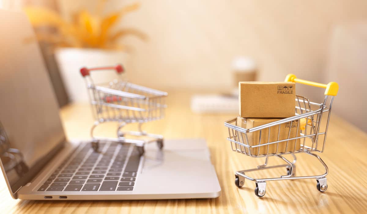 A laptop with a small shopping cart in front of it