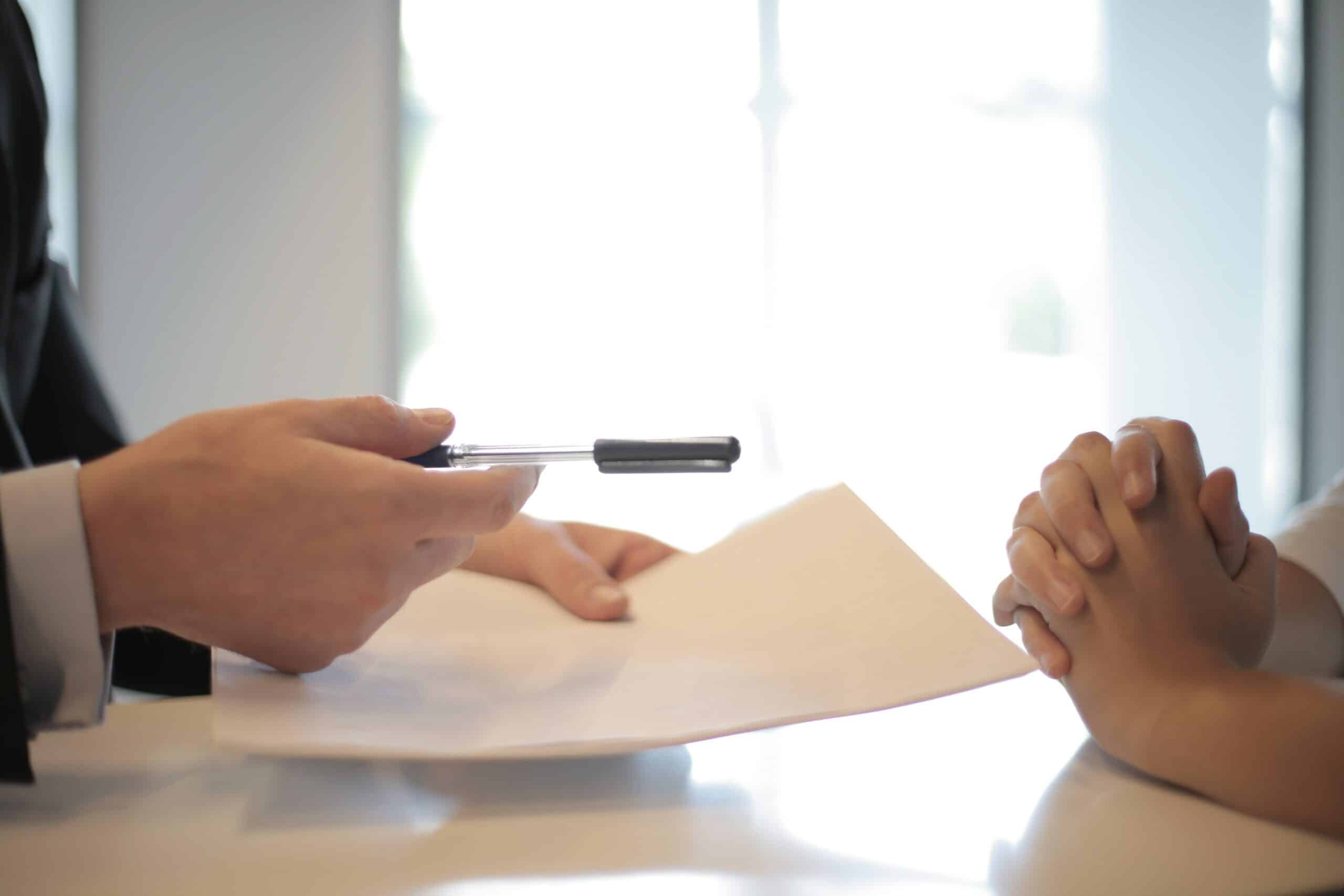 Partnership: man hands another person a pen to sign