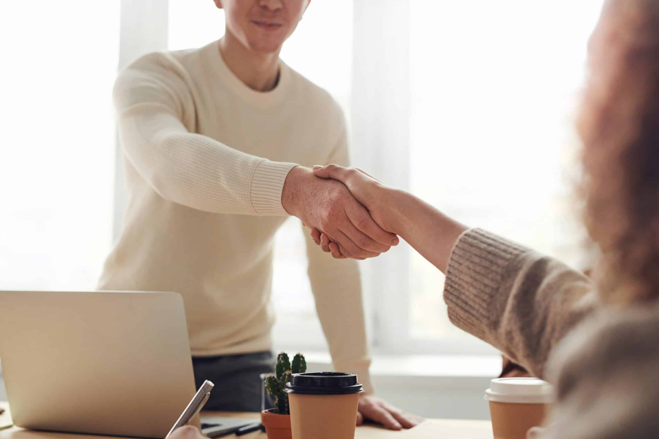 pexels-fauxels-3184465 Partnerschaft: Ein Mann reicht einer Frau im Meeting die Hand