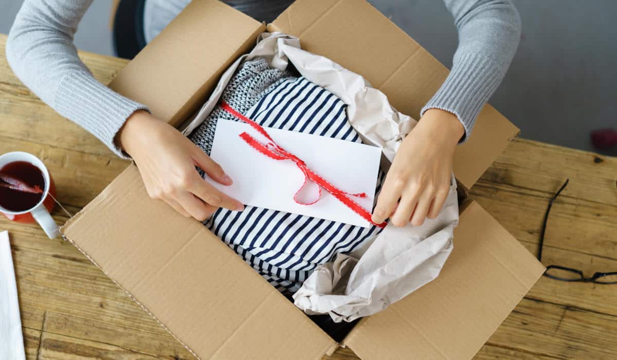Reaktives Retourenmanagement Frau packt ein Paket mit Kleidung aus