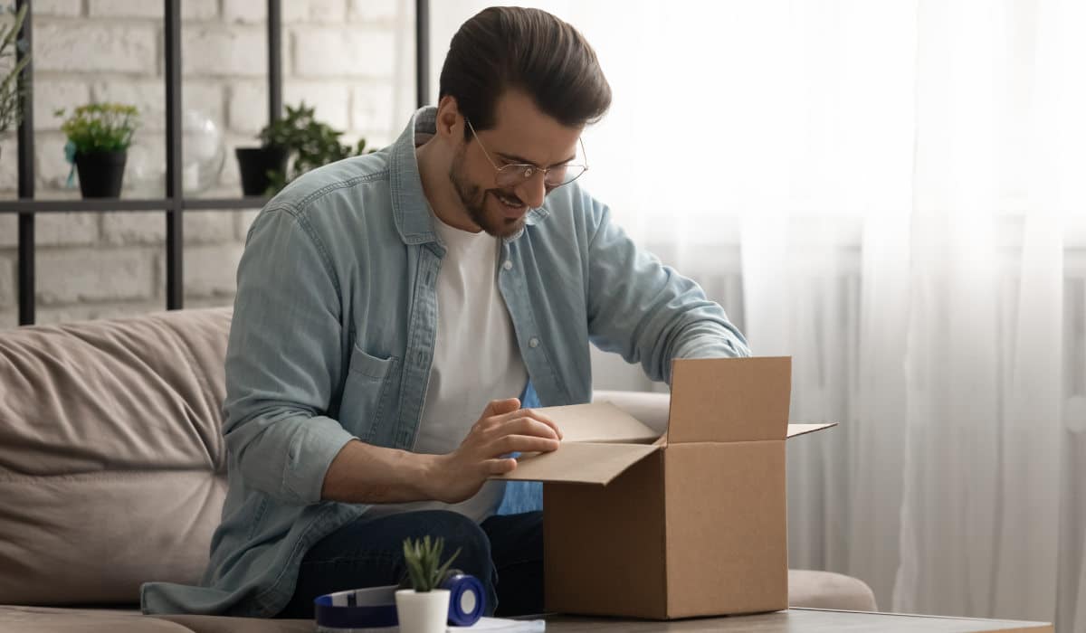 Track and trace shipment tracking Happy man unpacking a parcel