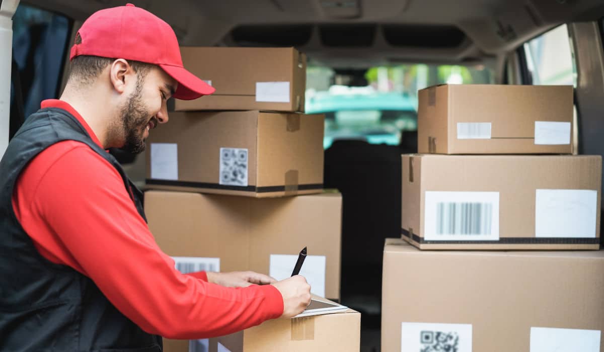 Paketdienstfahrer vor einem Stapel Pakete