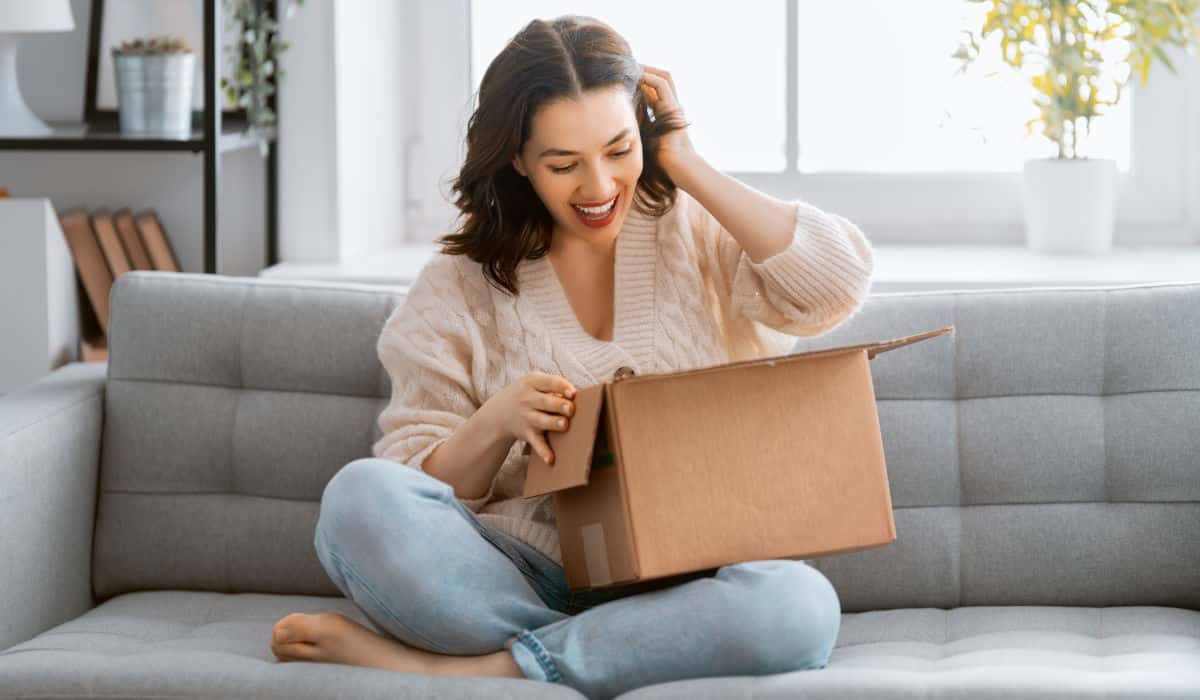 Woman sitting on a sofa opening a parcel