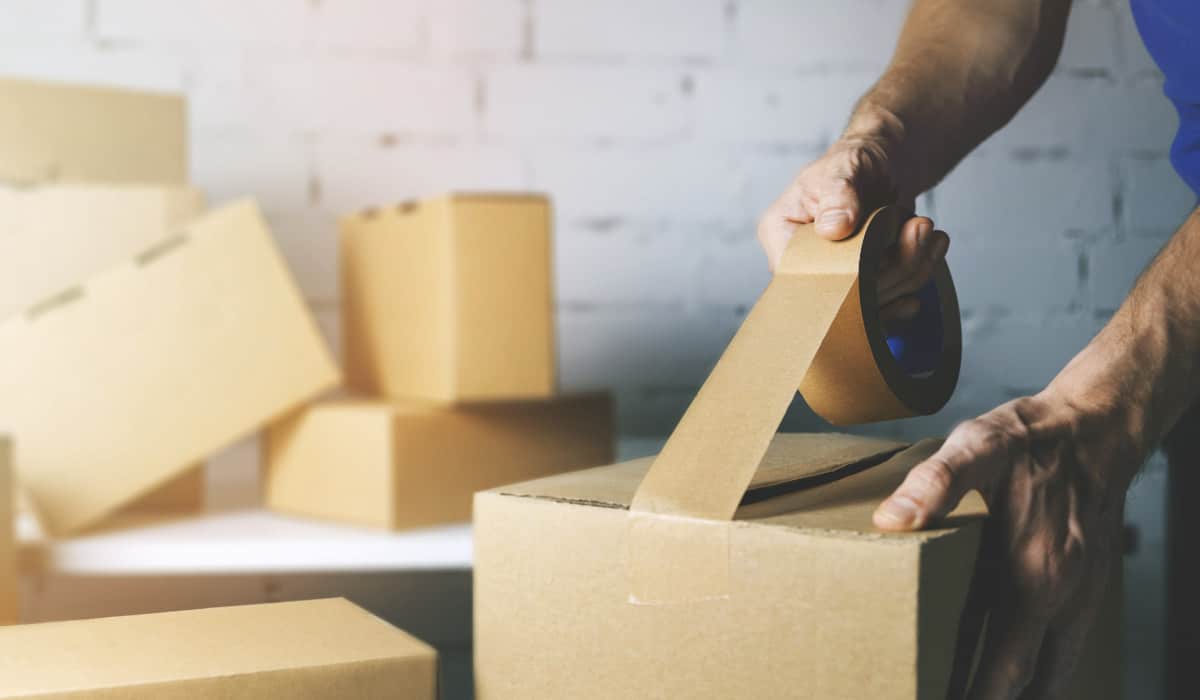 Retourenprozess optimieren Mann klebt Retourenpaket zu